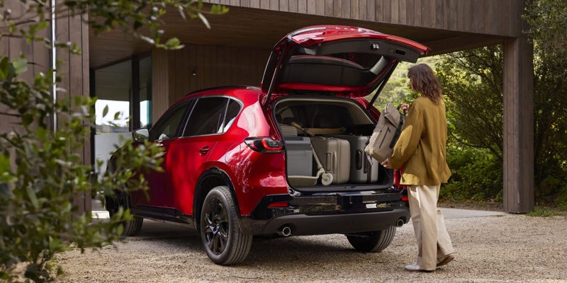 Woman loading luggage into a red SUV.